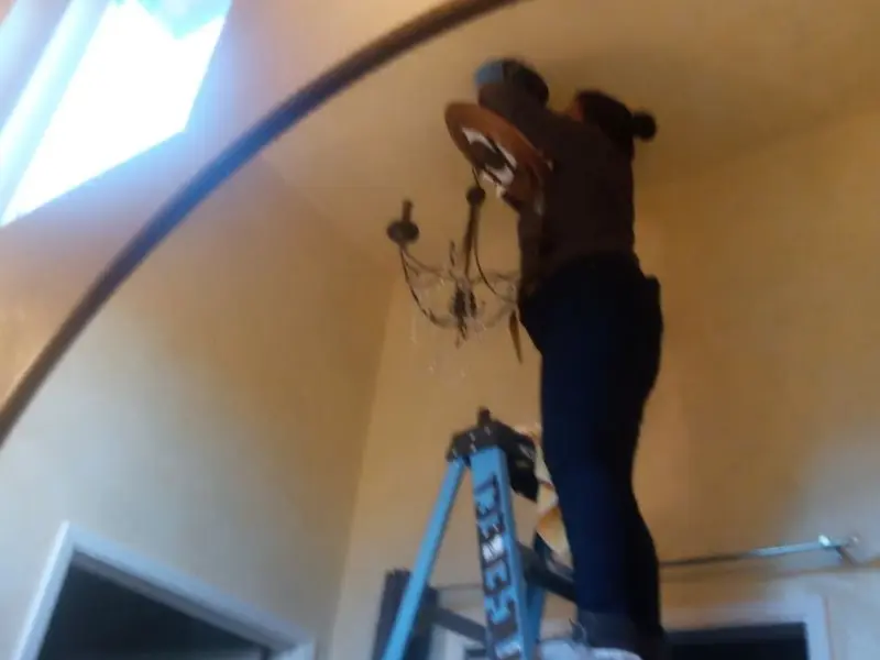 Electrician installing a chandelier in a Columbus residence